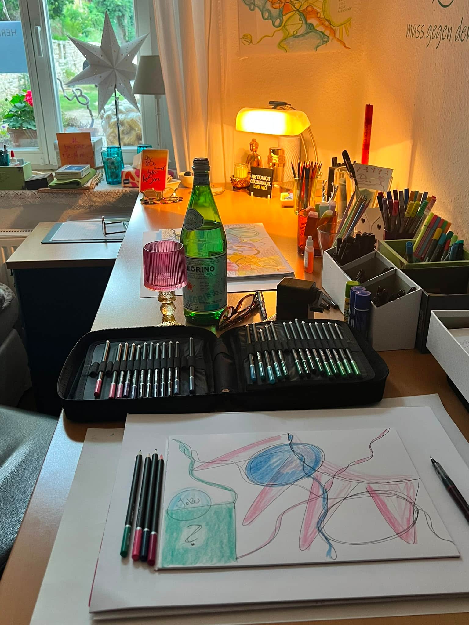 Der Atelier-Schreibtisch von Sarah Croé — Stifte, Aquarell und eine entstehende Zeichnung im warmen Abendlicht